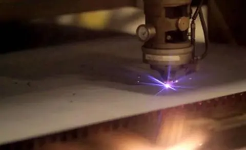 Bright light from a computer controlled laser as it cuts through sheet metal to fabricate parts.
