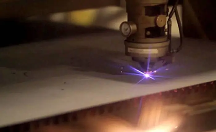 Une lumière vive émise par un laser contrôlé par ordinateur tandis qu'il découpe une plaque de métal pour fabriquer des pièces.