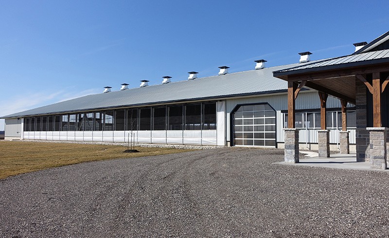 Grange avec un système de rideau partiellement ouvert et des cheminées sur le faîtage.